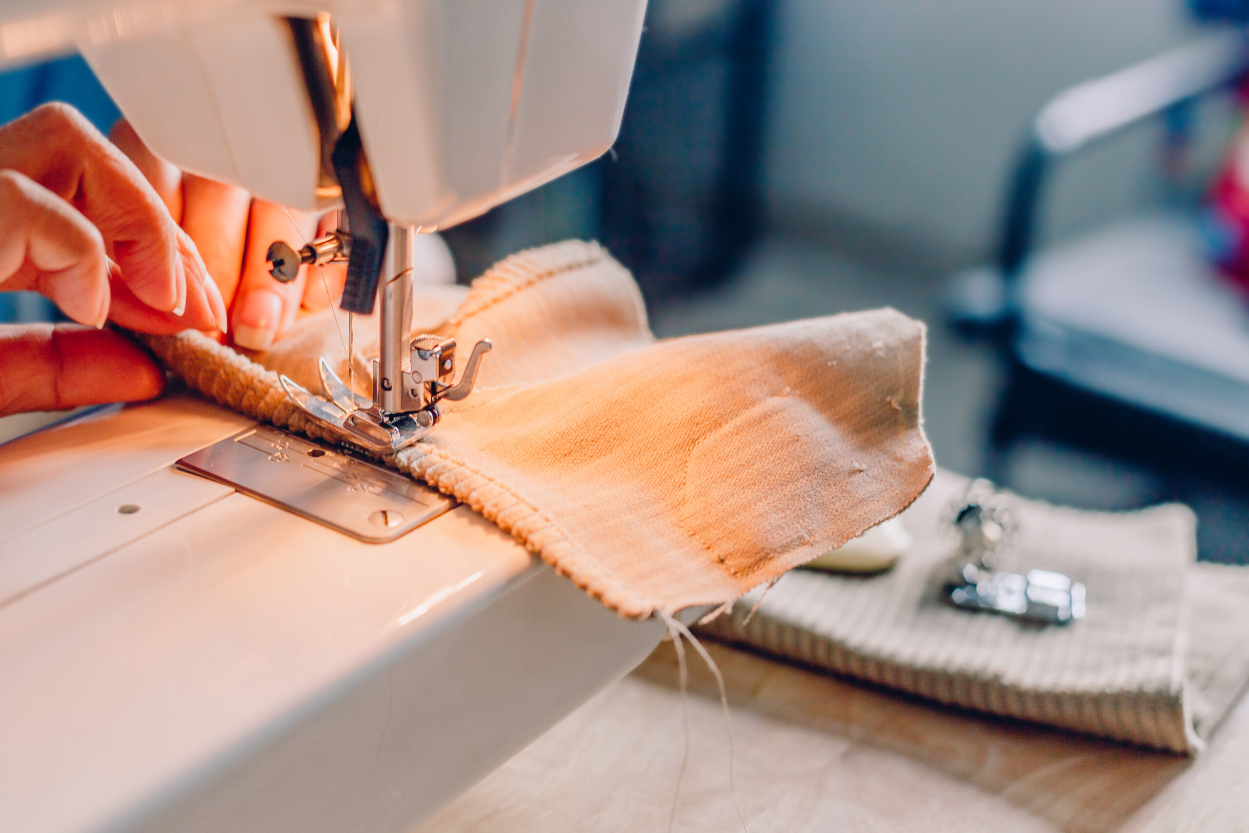 hands of sewing process. Female hands stitching fabric on machine hobby at home. blurred background.